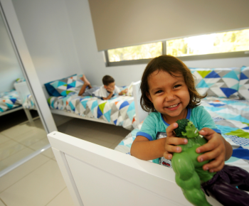 Child smiling, on bed with action figure